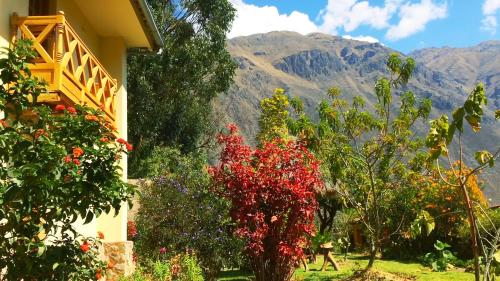 a house with trees and mountains in the background at Apu Lodge in Ollantaytambo