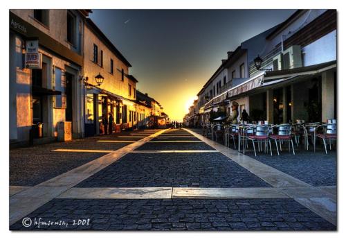 a cobblestone street with tables and chairs in a city at Porto Covo / Costa Alentejana in Porto Covo