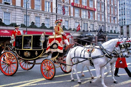 a man riding in a horse drawn carriage on a street at Rubens At The Palace in London