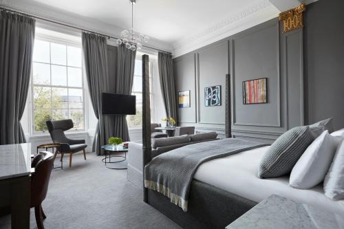 a bedroom with a king sized bed and a living room at Kimpton - Blythswood Square Hotel, an IHG Hotel in Glasgow