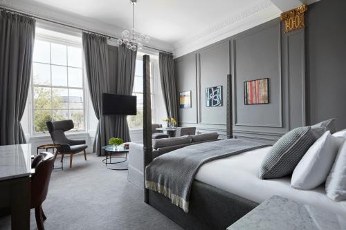 a bedroom with a king sized bed and a living room at Kimpton Blythswood Square Hotel & Spa by IHG in Glasgow