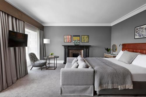 a bedroom with a bed and a couch and a fireplace at Kimpton - Blythswood Square Hotel, an IHG Hotel in Glasgow