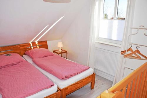 BlieschowFerienwohnung Anja的卧室里有两张床，床单是粉色的，还有一扇窗户