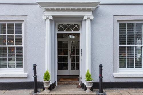 a white house with a door and two potted plants at The Summer House in Penzance