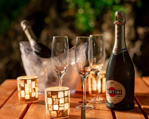 Una botella de champán y cuatro copas de vino en una mesa de madera. en Okinawa BBQ Glamping, en Nakijin