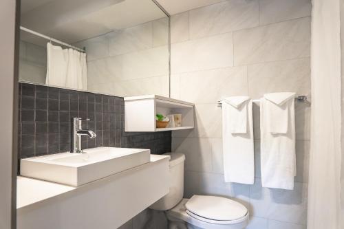 a white bathroom with a sink and a toilet at Hôtel Marineau La Tuque in La Tuque