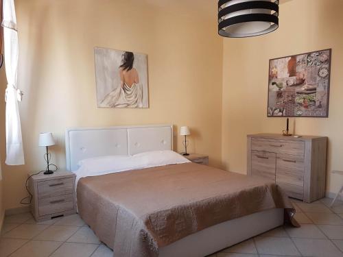 een slaapkamer met een bed, 2 dressoires en een schilderij bij Appartamenti Via La Marmora in Teulada