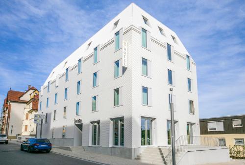 un edificio blanco con un coche azul estacionado frente a él en Hotel Bergamo, en Ludwigsburg