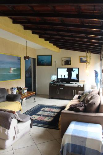 a living room with a couch and a flat screen tv at Rio Surf House Hostel e Pousada in Rio de Janeiro