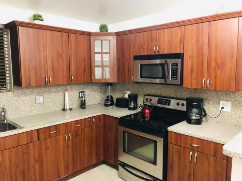 - une cuisine avec des placards en bois, une cuisinière et un four micro-ondes dans l'établissement The Heart of Wynwood, à Miami