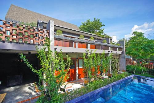 a house with a swimming pool in front of a building at Yellow Pillow village in Chiang Mai