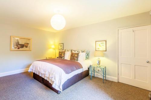 1 dormitorio con cama, lámpara y puerta en Luxury Apartments - 22 Garden Flat, en Cheltenham