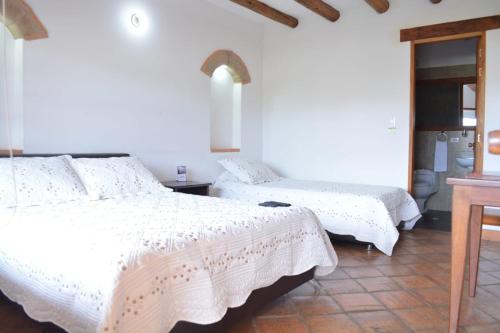 a bedroom with two beds with white comforters at La Foguera Sutamarchán in Sutamarchán