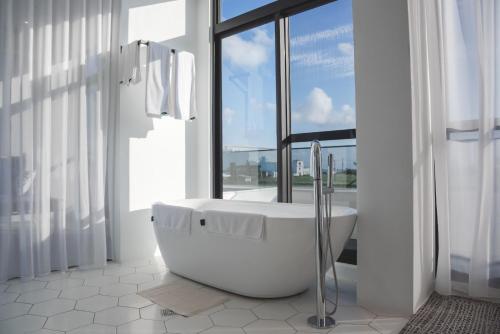 uma casa de banho branca com uma banheira e uma janela em Cloud 9 Panorama em Eluan