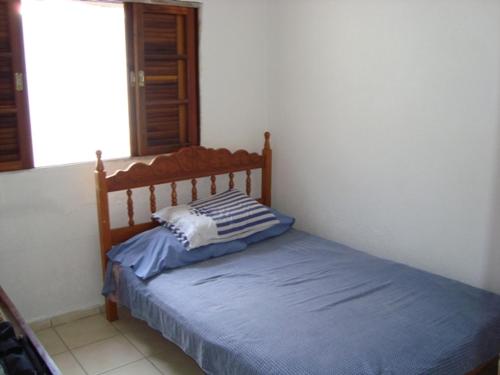een slaapkamer met een bed met een houten hoofdeinde bij Casa arejada e espaçosa in Bertioga