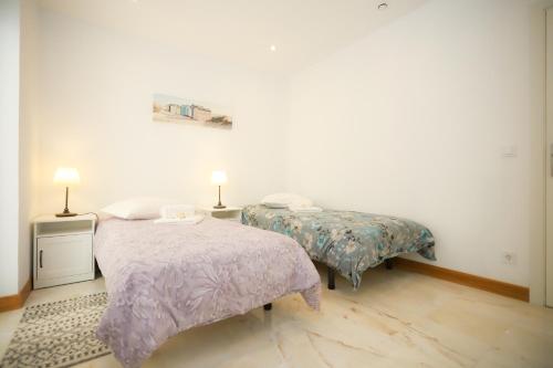 1 dormitorio con 2 camas y 2 lámparas. en Apartamento Casino Praia IV, en Figueira da Foz