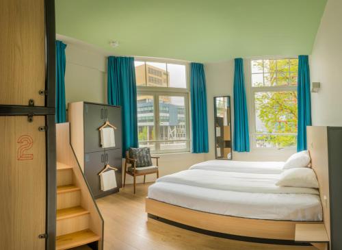 a bedroom with a large bed with blue curtains at Sparks Hostel in Rotterdam