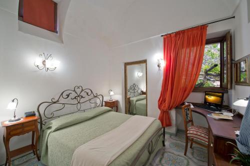 1 dormitorio con cama, escritorio y ventana en L'Antico Borgo Dei Limoni, en Amalfi