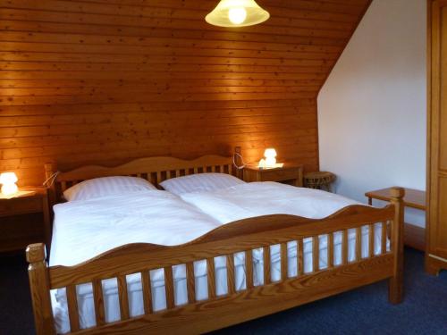 a bedroom with a large wooden bed with two lamps at Hotel-Pension Stöber in Jever