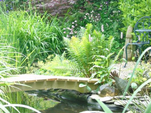 a bridge over a pond in a garden at The Old School B&B in Chichester