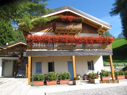 ein Haus mit roten Blumen auf dem Balkon in der Unterkunft Magdalenablick in Villnöss