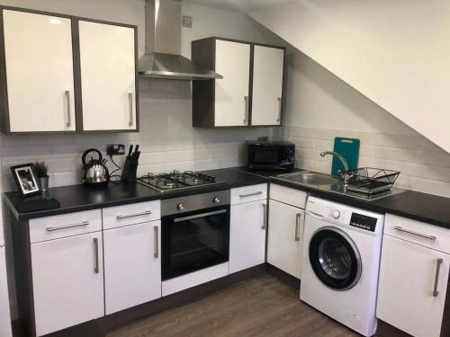 a kitchen with white cabinets and a washing machine at Spacious 1 Bed Apartment In The City Centre in Cardiff