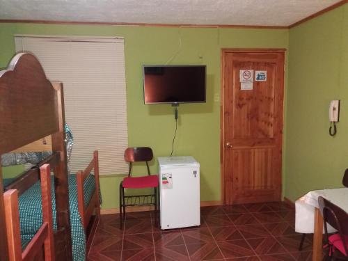 a room with a small refrigerator and a television at Alojamiento Valle Verde in Isla de Maipo