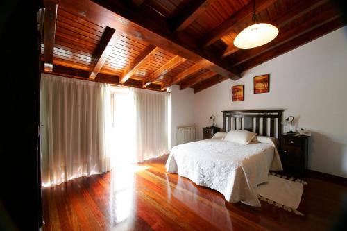 a bedroom with a bed and a large window at Casa da Botica A Estrada in Os Casares