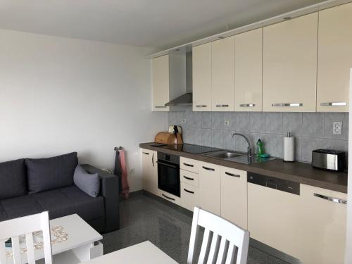 a kitchen with white cabinets and a couch at Apartments Diana in Šmrika
