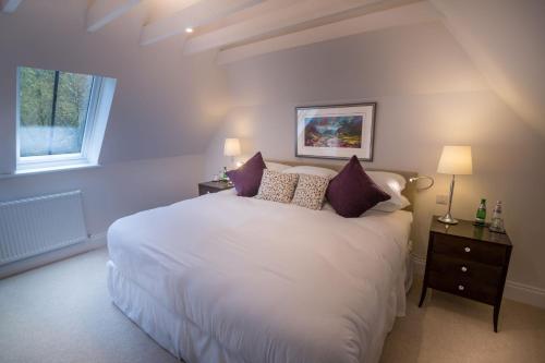 a bedroom with a large white bed with purple pillows at Glencoe House in Glencoe