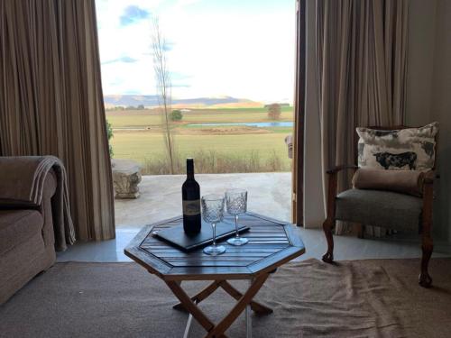 a living room with a wine bottle and glasses on a table at KarMichael Farm in Himeville