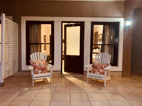 two white chairs sitting in a room with windows at KarMichael Farm in Himeville