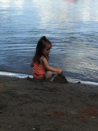 a little girl playing in the sand on the beach at Little Hawk Resort & Marina in Algonquin Highlands
