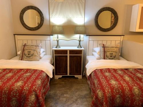 two beds in a room with two mirrors at KarMichael Farm in Himeville