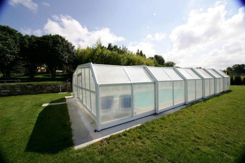 une grande serre en verre dans un champ d'herbe dans l'établissement Casa da Botica A Estrada, à Os Casares