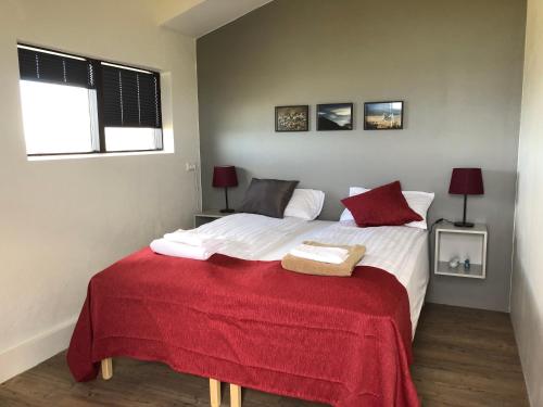 um quarto com uma cama grande e um cobertor vermelho em Guesthouse Gimbur em Reykjarholl