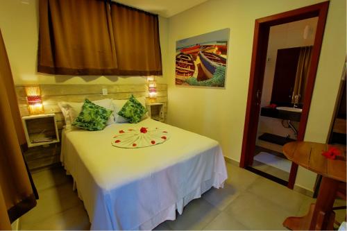 a bedroom with a white bed with a plate on it at Pousada Vila Boa Vida in Bombinhas