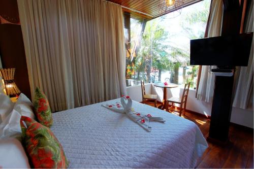 a bedroom with a bed with a white blanket and a window at Pousada Vila Boa Vida in Bombinhas