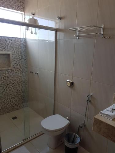 a bathroom with a toilet and a glass shower at Hotel Barretos in Barretos