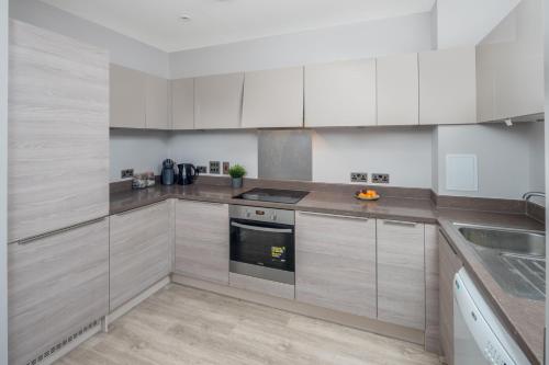 a kitchen with white cabinets and a stove at Vertex Luxury Suite in Croydon