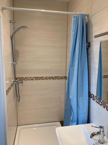 a shower with a blue shower curtain next to a sink at Apart-Hotel Rheinischer Hof Dormagen in Dormagen