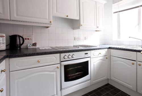 a white kitchen with white cabinets and an oven at MAYFAIR PRIME APARTMENTS in London