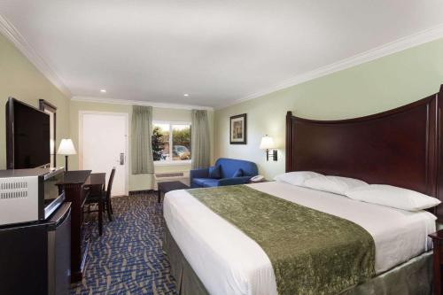 a hotel room with a large bed and a desk at Travelodge by Wyndham Orange County Airport/ Costa Mesa in Costa Mesa