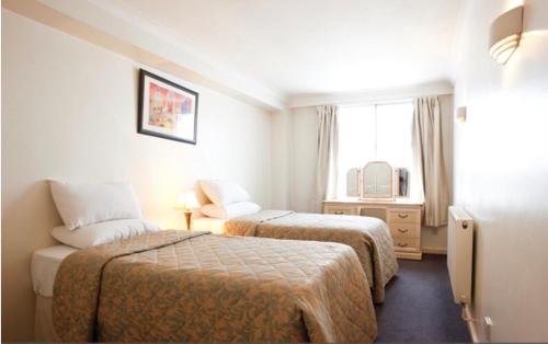 a hotel room with two beds and a window at MAYFAIR PRIME APARTMENTS in London
