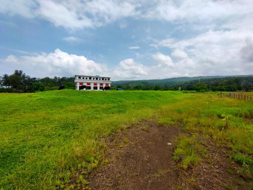 a large field with a white building in the distance at Shobha Farmhouse in Kashid
