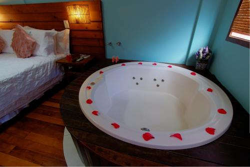 a large bath tub in a room with a bed at Pousada Vila Boa Vida in Bombinhas