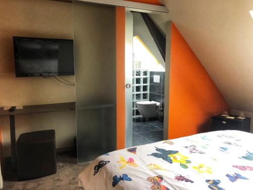 a bedroom with a bed and a flat screen tv at La table d’Auguste in Dour
