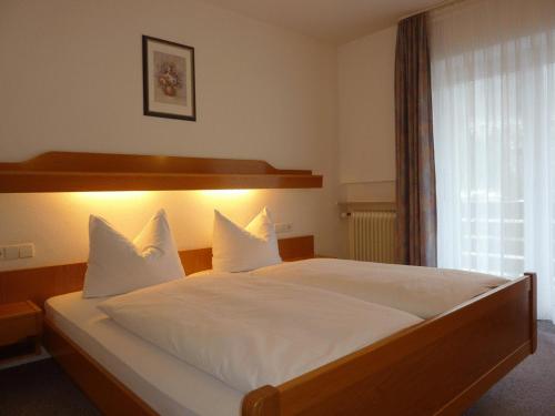 Schlafzimmer mit einem Bett mit weißer Bettwäsche und einem Fenster in der Unterkunft Ferienwohnungen Schwarzwald Panorama in Bad Wildbad