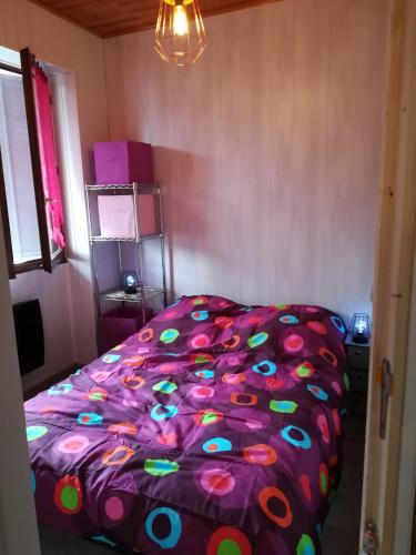 - un lit avec une couette colorée dans une chambre dans l'établissement Appartement au coeur de la maurienne, à Saint-Étienne-de-Cuines