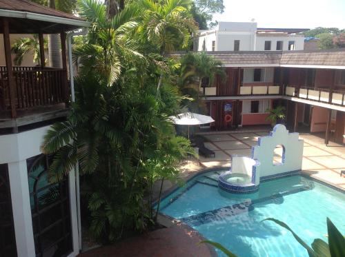 a pool in the courtyard of a building with palm trees at Hotel Normandie Limited in Port-of-Spain